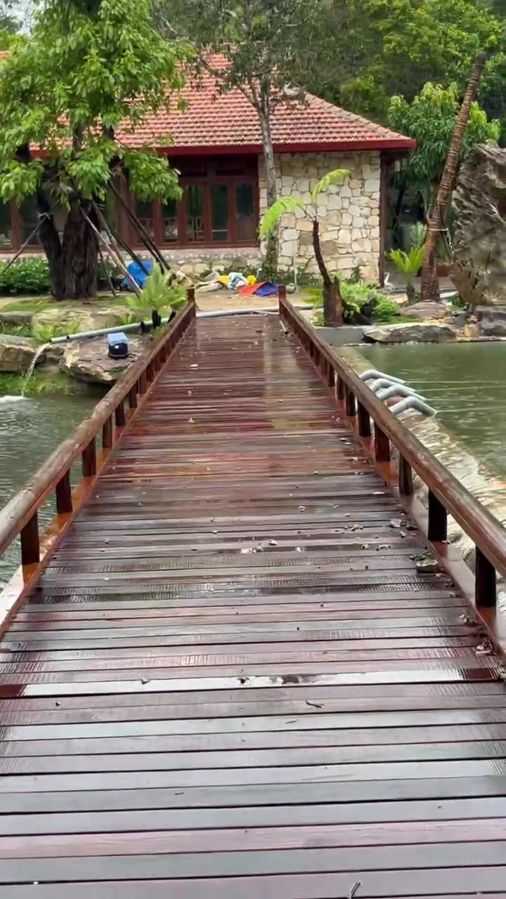 Cầu gỗ dẫn vào pavilion chính bên hồ nước tại Rivora Retreat